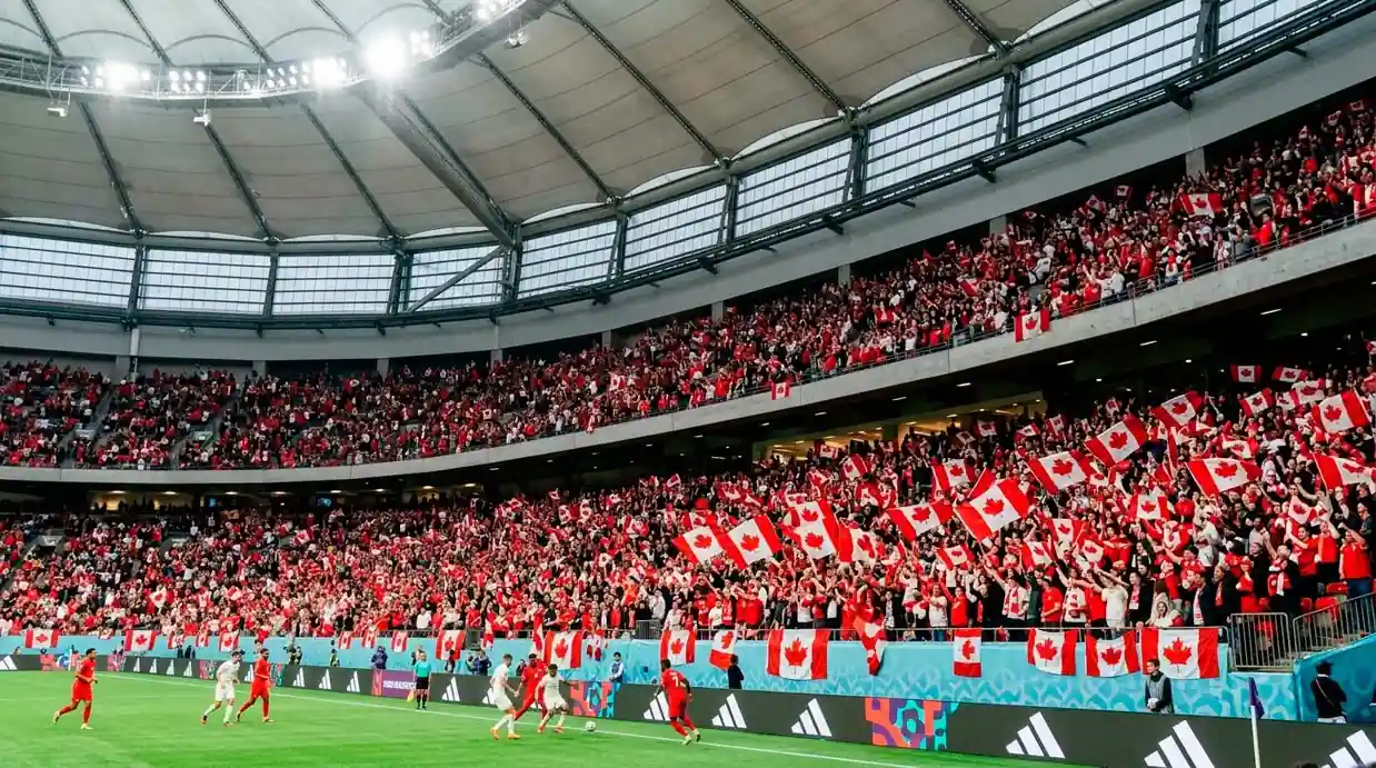 A packed BC Place stadium in Vancouver with Canadian red-and-white flags filling the stands ahead of a World Cup match